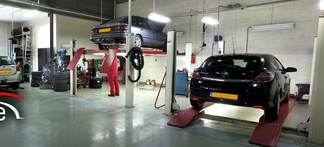 De werkplaats van Car Care Rotterdam met hefbruggen en een monteur in een rode overall